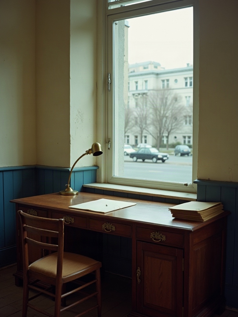 Dnipro property desk with oak table, brass lamp, and stacked lease folders by a street window